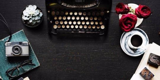 Dark wooden desk with typewriter and flowers