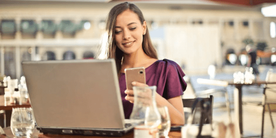 woman at a cafe conducting business on her phone and computer