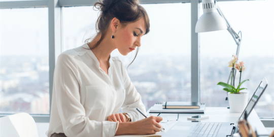 women taking notes on laptop