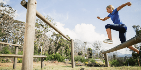 Woman leaping from one rock across chasm to another rock