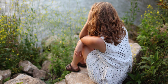 stressed woman sitting by a pond