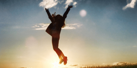 woman jumping in front of sunrise