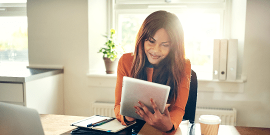 woman sitting at a table looking at her iPad