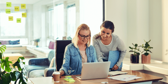 Two female colleagues speak and work together 