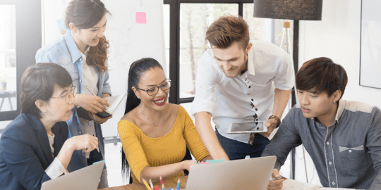 team members gathered around a laptop brainstorming