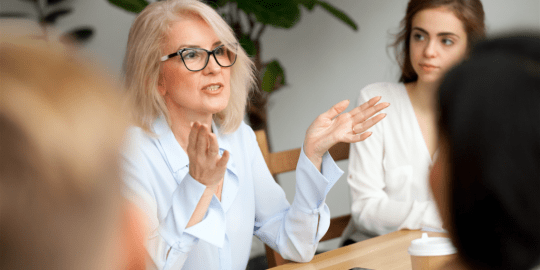 Business woman speaking in front of a laptop displaying data and charts