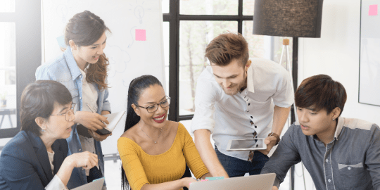 diverse group of employees gathered around a laptop