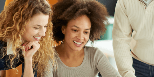group of young workers gathered around a computer