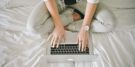 woman typing on bed
