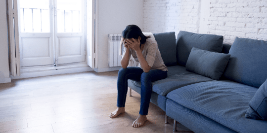 woman on couch with her head in her hands