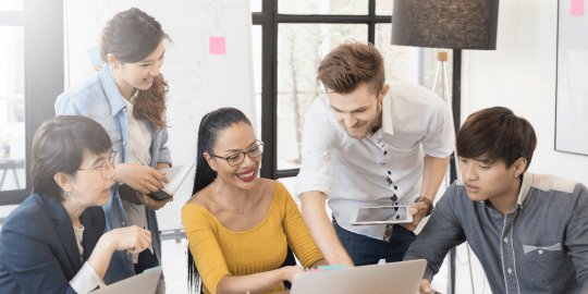 colleagues gathered around a computer talking