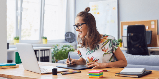 woman jotting down ideas in front of a laptop