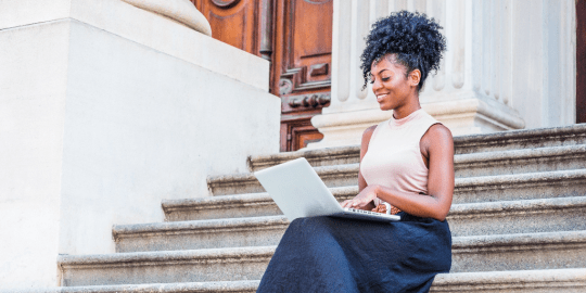 professional woman sitting on steps working on a computer