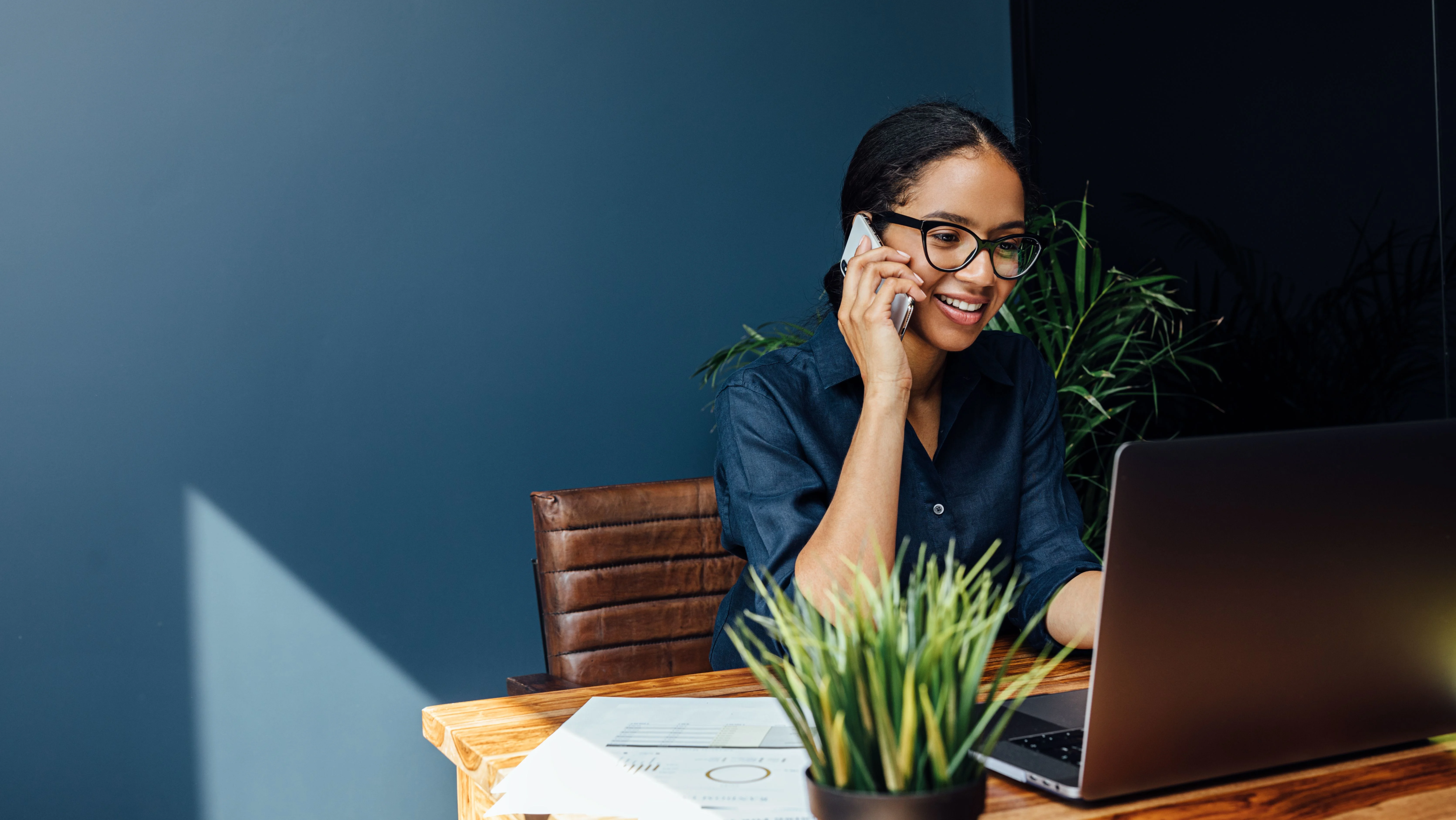 Woman talking on her cellphone while looking at laptop.