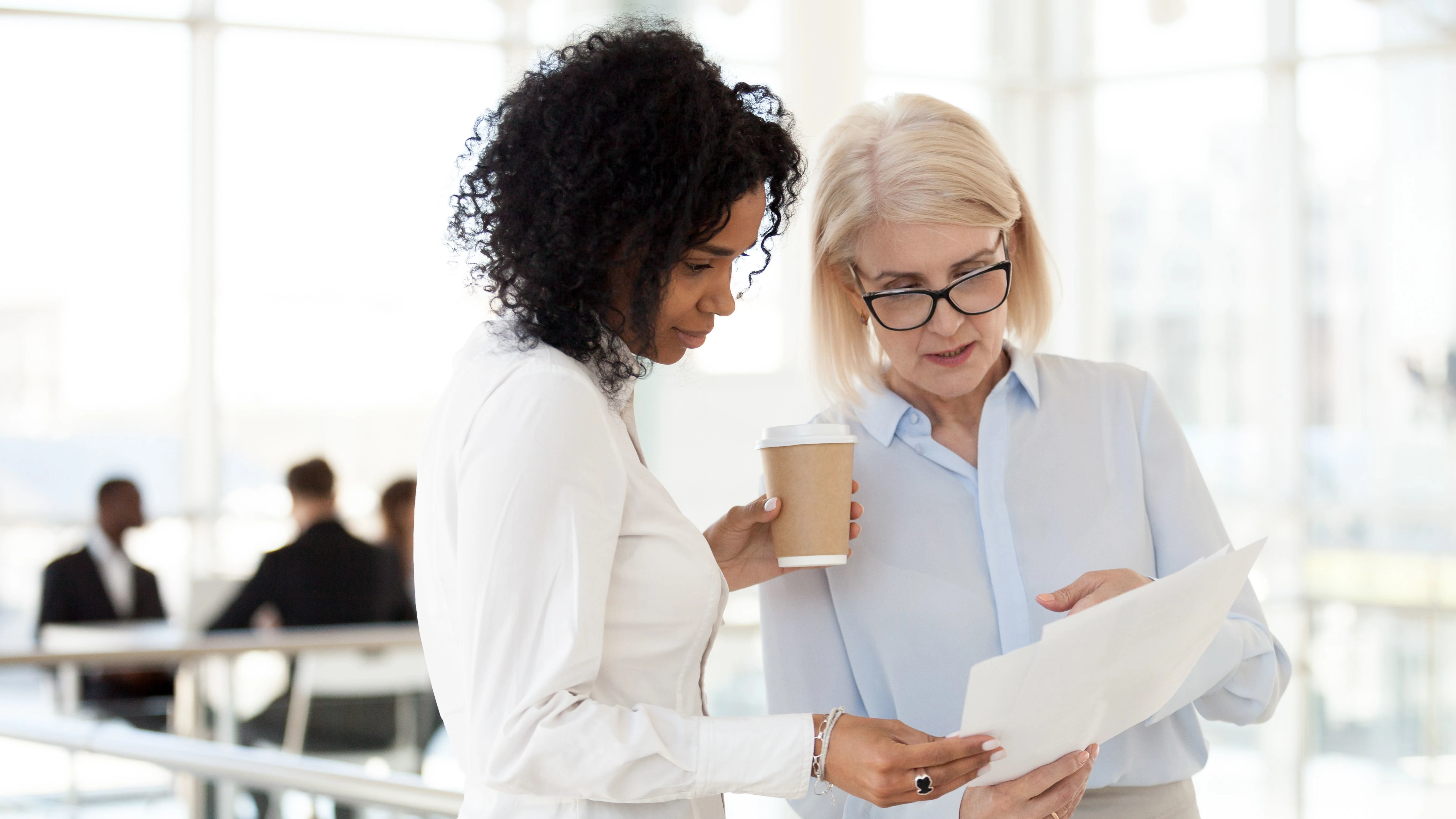 younger and older colleagues looking at a report and chatting