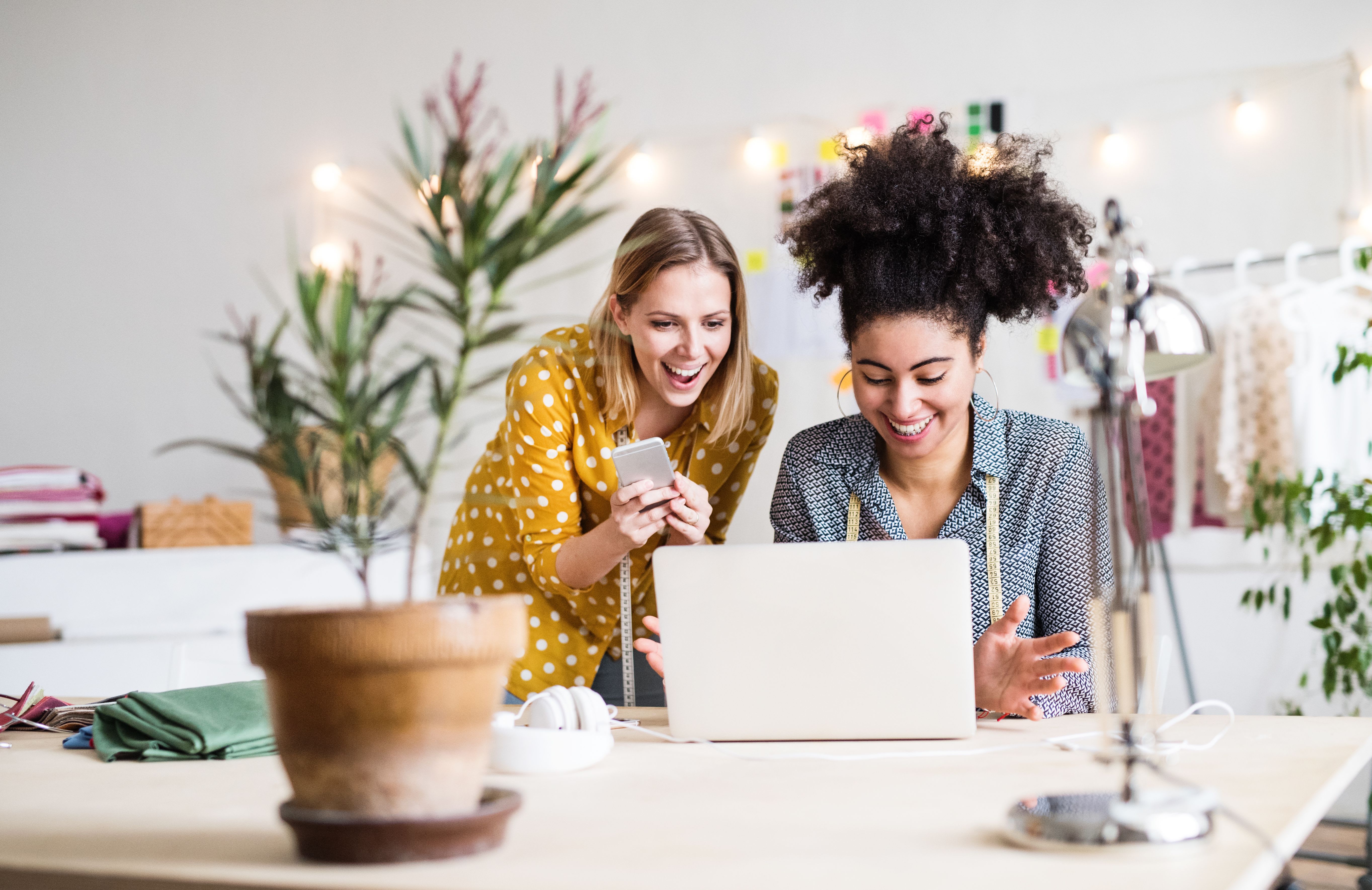 Two coworkers smile and look at a laptop