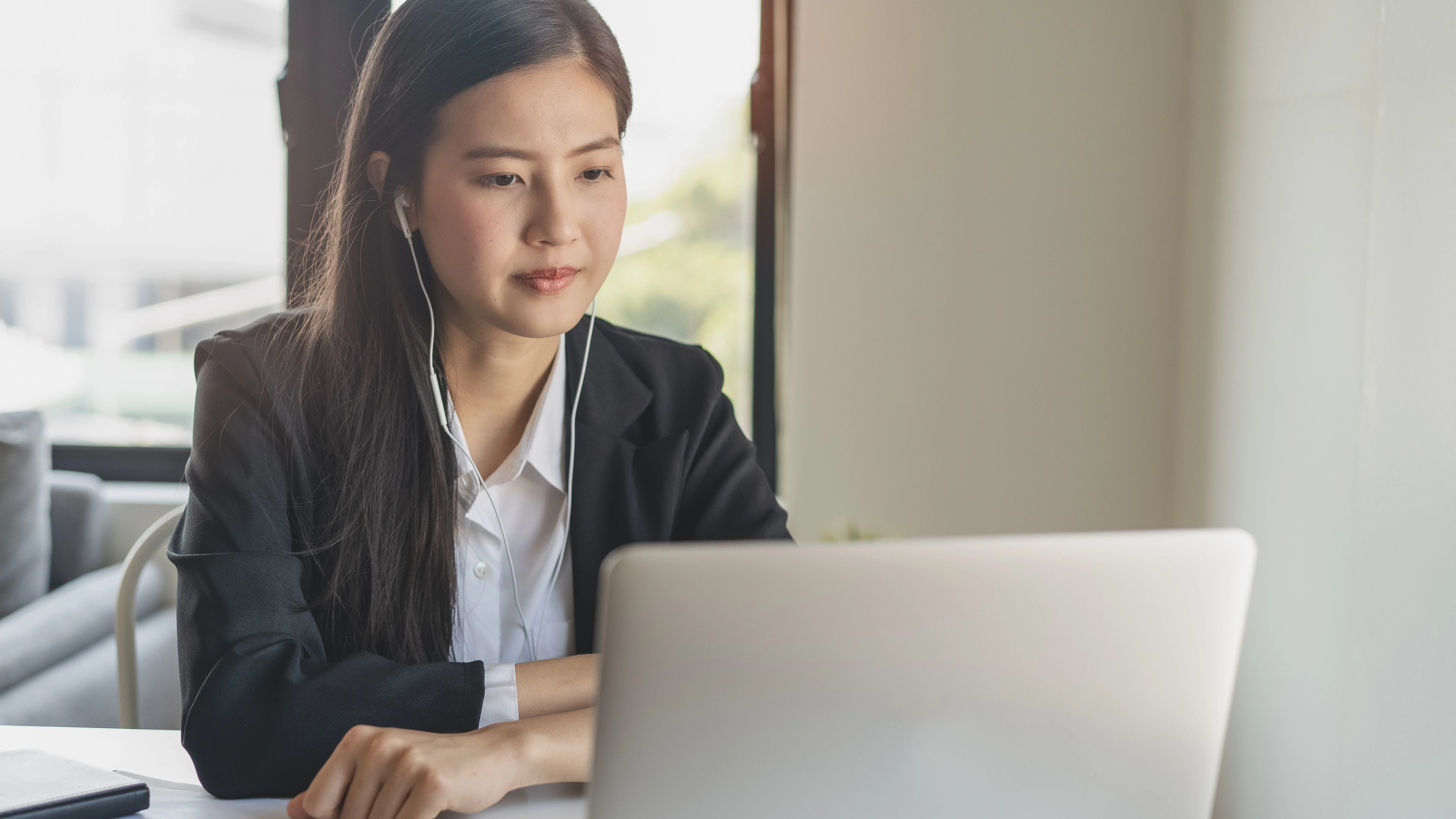 Woman with headphones staring at laptop in front of her.