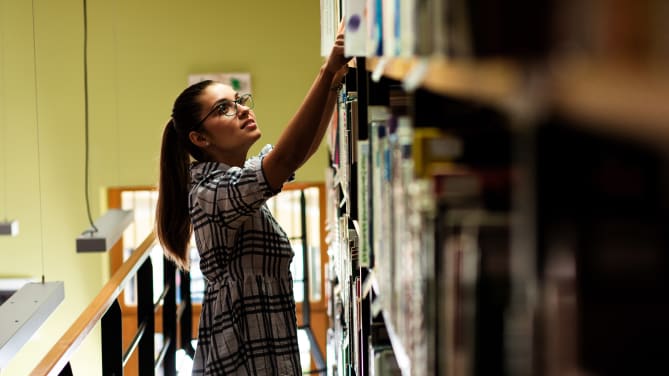 librarian getting a book from the shelf of a library