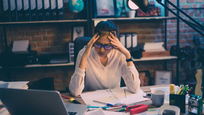 woman with a messy desk at work looking stressed