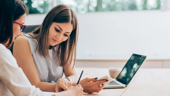 two woman looking at a document