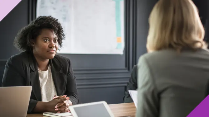 Two women at an office having a meeting, to illustrate the importance of learning how to negotiate your promotion salary as a woman