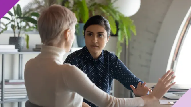 white woman speaking to indian woman at an office