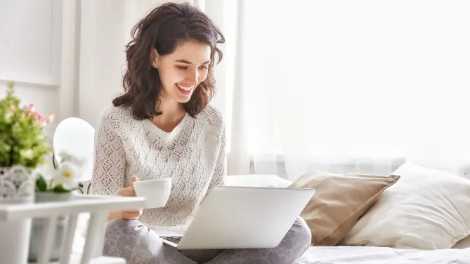 woman working on a laptop on her bed