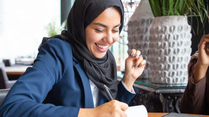 woman writing by hand on a pad of paper
