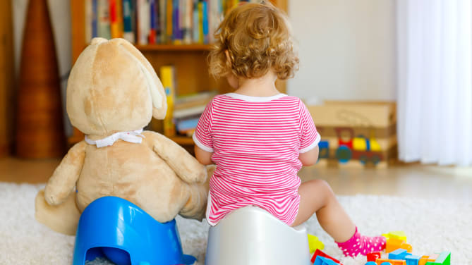Child on potty next to stuffed animal