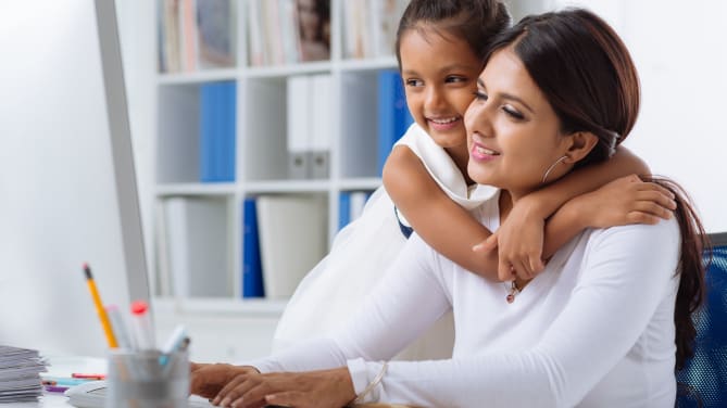 daughter hugging mother while she works