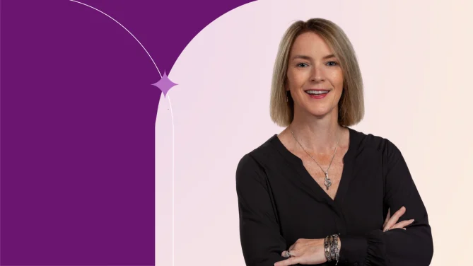 Michelle in front of a pink background, wearing a black blouse smiling