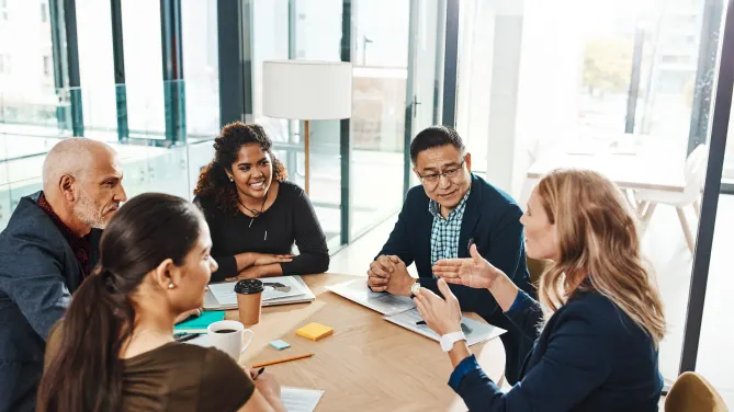 Five people have a discussion at a table.