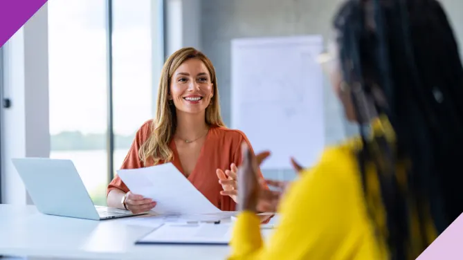 Two professionals in an office setting, one holding a paper, illustrating key skills to put on a resume