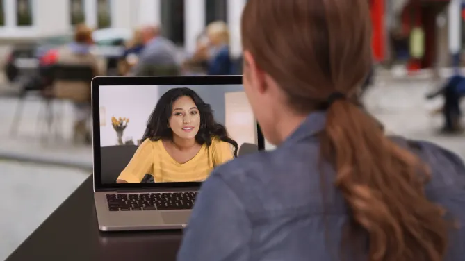 two women at work having a conversation via video vall