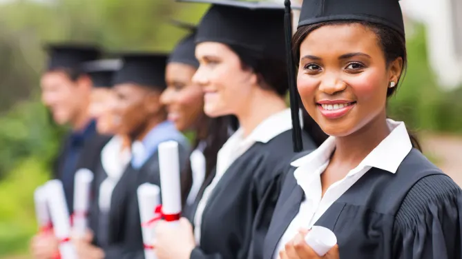 graduates in caps and gowns holding diplomas