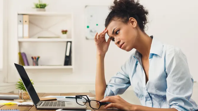Woman with hand on her head, looking frustrated at her computer.