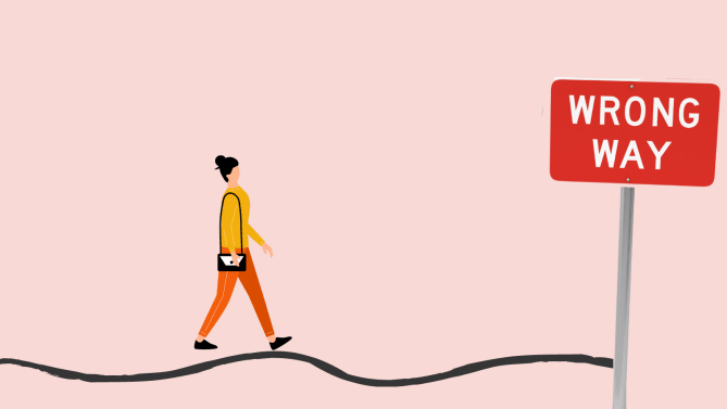 woman walking toward "wrong way" sign