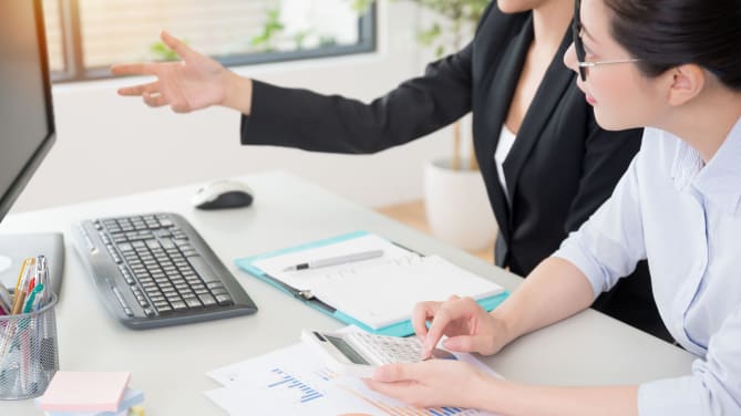 Businesswomen calculating price elasticity