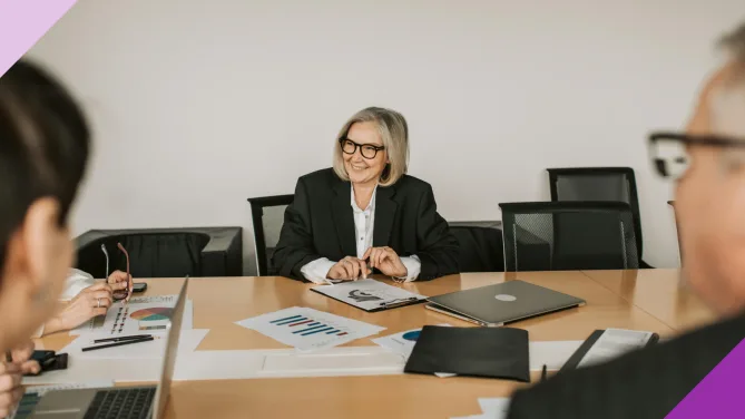 A senior woman happy in a work meeting to illustrate that it's possible to do a career change at 50