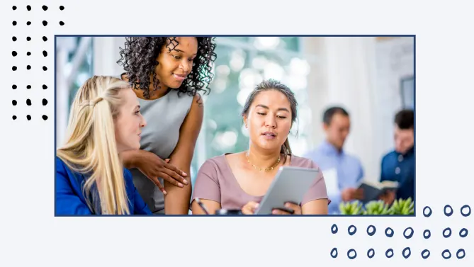 Three woman looking at a tablet at work. 