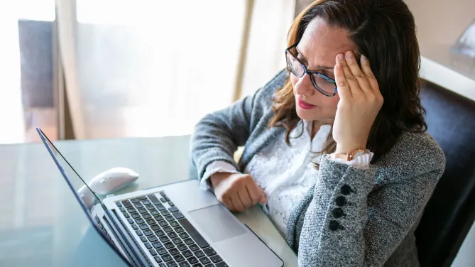 woman sitting in front of her laptop looking frustrated