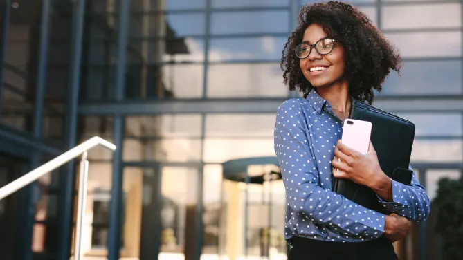 professional holding folders outside her office, smiling