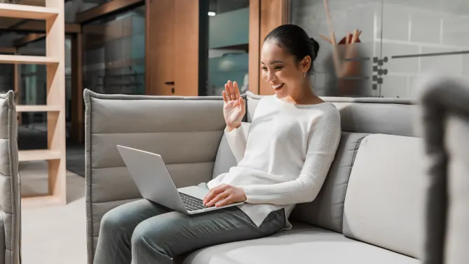 joyful woman waving into laptop