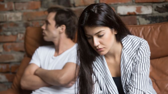 couple sitting on the couch looking tense