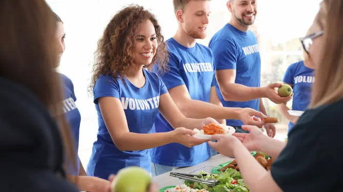 Volunteers serving food to people indoors
