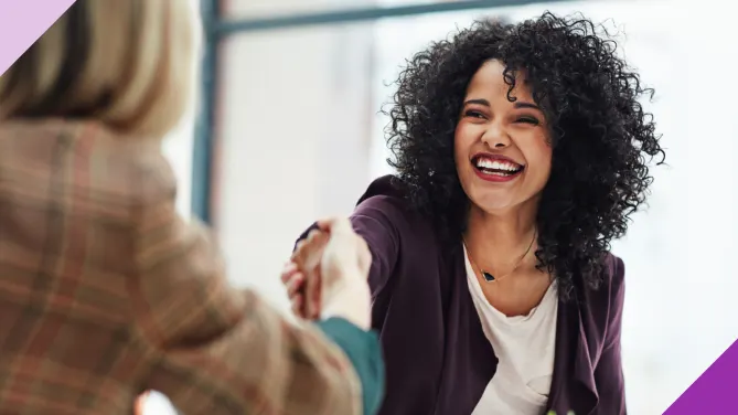 Two colleagues shaking hands in an office setting, representing qualities that make managers want to promote someone