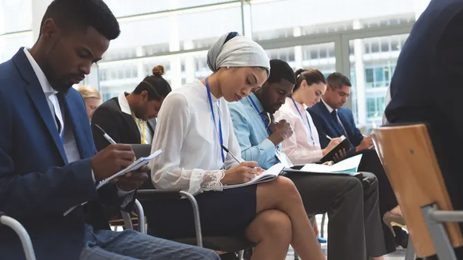 group of people in conference setting reading paper on clipboard