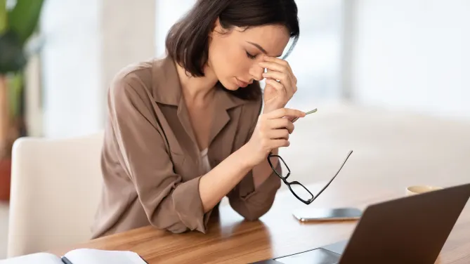 woman in front of laptop with head in hands