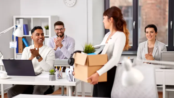 woman leaving the office carrying a box of her possessions