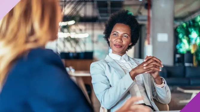 Two women discussing strategies for negotiating a raise in a meeting.